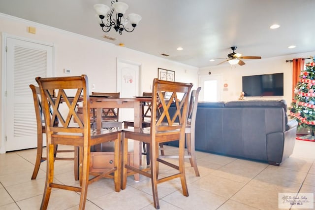 tiled dining area with ceiling fan with notable chandelier and crown molding