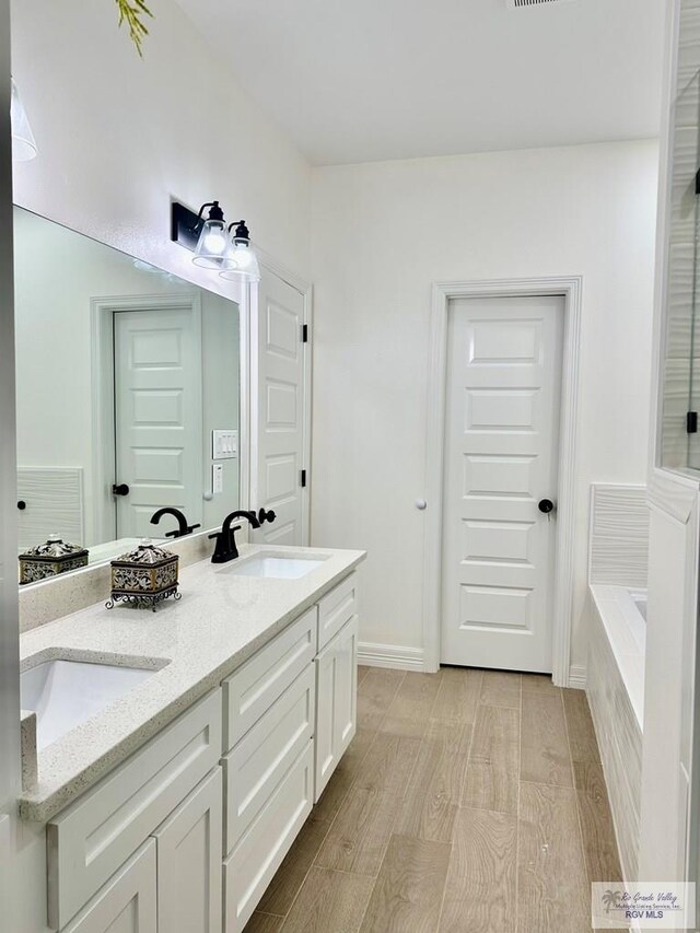 1521 Stirrup Cir, San Benito, TX 78586 - full bathroom featuring wood finished floors, double vanity, a garden tub, and baseboards