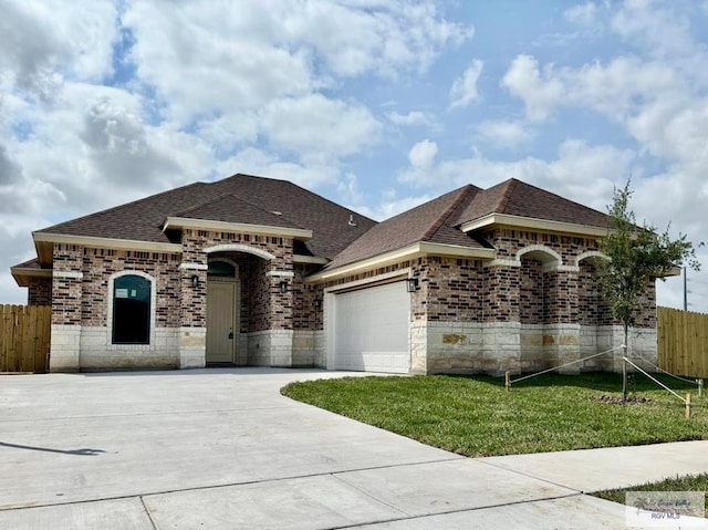 1521 Stirrup Cir, San Benito, TX 78586 - french country inspired facade with an attached garage, roof with shingles, driveway, and brick siding