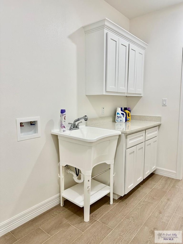 1521 Stirrup Cir, San Benito, TX 78586 - laundry room featuring washer hookup, wood finish floors, baseboards, and cabinet space