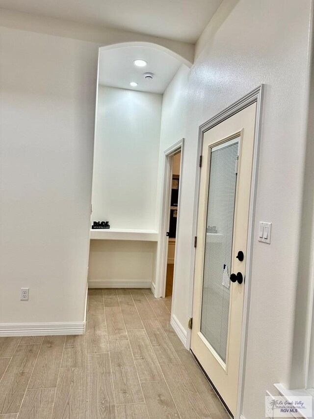 1521 Stirrup Cir, San Benito, TX 78586 - hall featuring light wood finished floors, arched walkways, and baseboards