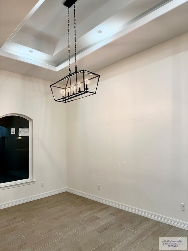 1521 Stirrup Cir, San Benito, TX 78586 - unfurnished room with wood finished floors, baseboards, a raised ceiling, and a chandelier