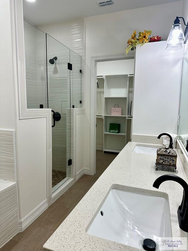 1521 Stirrup Cir, San Benito, TX 78586 - bathroom featuring a shower stall, double vanity, a spacious closet, and wood finished floors