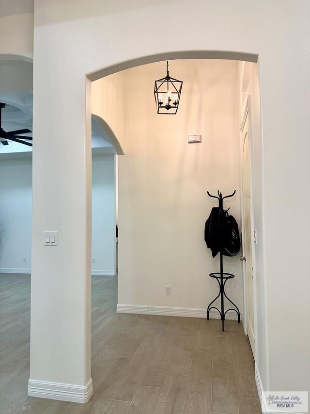 1521 Stirrup Cir, San Benito, TX 78586 - hallway with arched walkways, wood finished floors, a chandelier, and baseboards