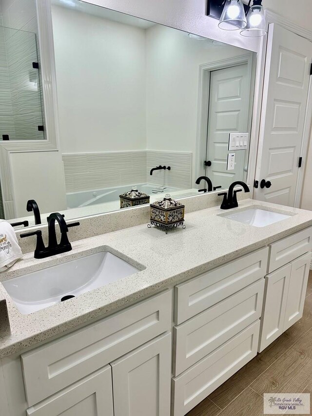 1521 Stirrup Cir, San Benito, TX 78586 - bathroom with double vanity, wood finished floors, and a tile shower