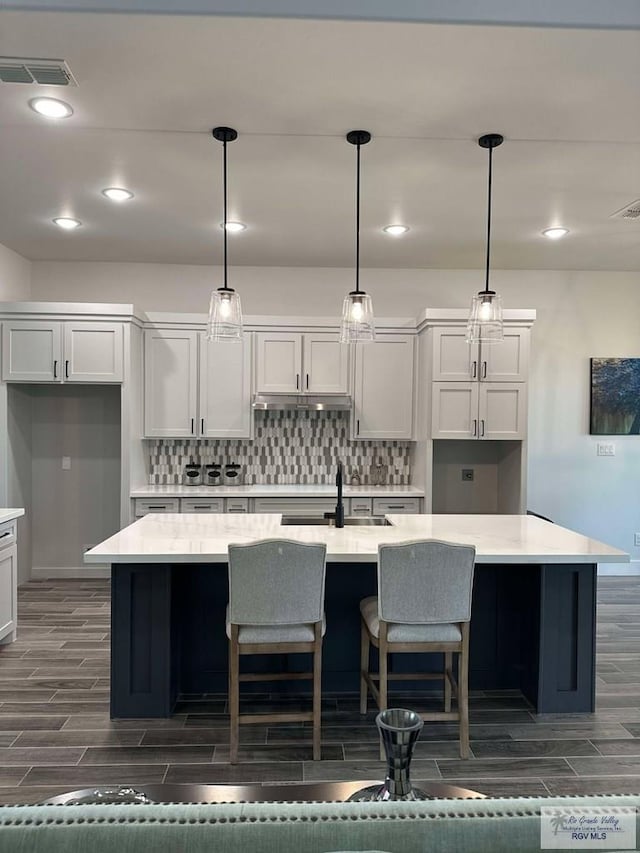 3518 Treasure Hills Blvd, Harlingen, TX 78550 - kitchen featuring wood finish floors, backsplash, light countertops, an island with sink, and recessed lighting