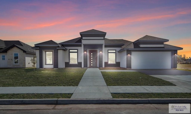 prairie-style house featuring a garage and a lawn