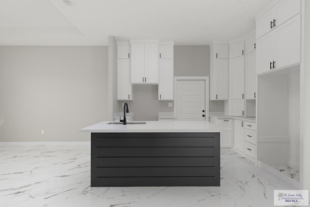 kitchen with white cabinetry, an island with sink, and sink