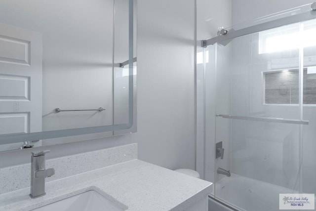 full bathroom featuring vanity, toilet, and bath / shower combo with glass door