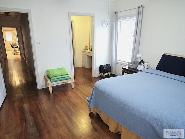 bedroom with ensuite bathroom and dark hardwood / wood-style flooring