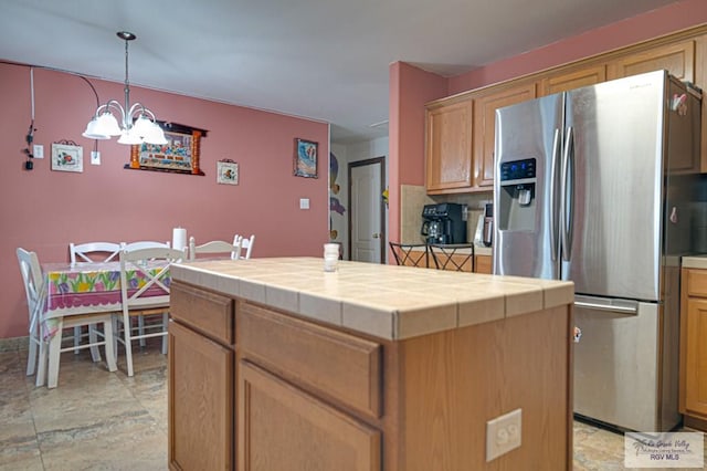 kitchen featuring pendant lighting, backsplash, a center island, tile counters, and stainless steel refrigerator with ice dispenser