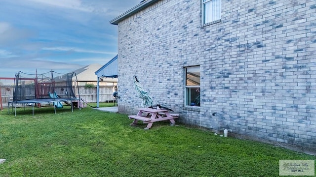 view of side of property featuring a yard and a trampoline