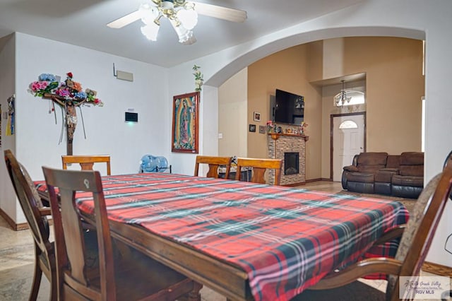 dining space featuring a stone fireplace, vaulted ceiling, and ceiling fan