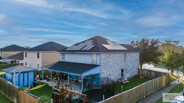 back of property with a yard, a patio area, a shed, and solar panels