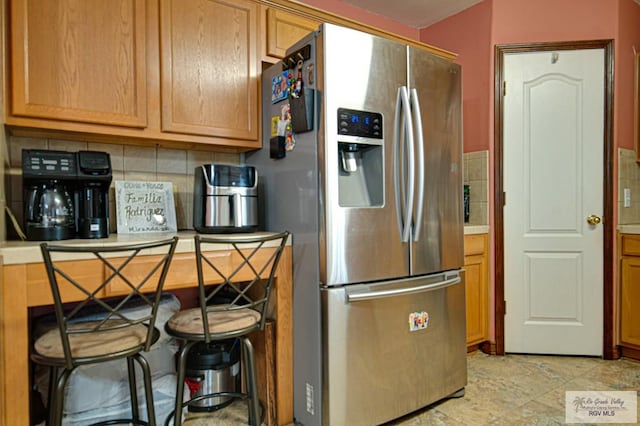 kitchen with stainless steel fridge with ice dispenser and decorative backsplash