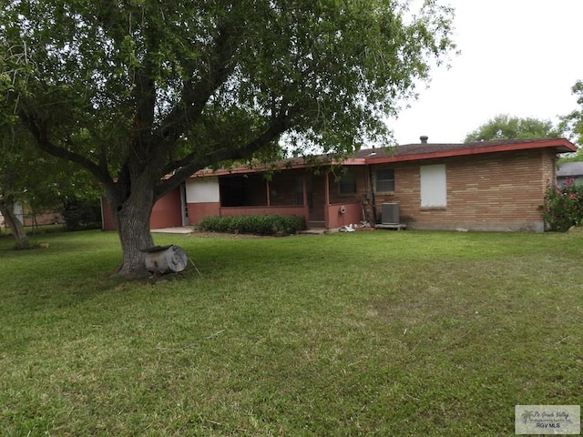 55 Carlton Dr, Brownsville, TX 78521 - rear view of house featuring central AC unit, a lawn, and brick siding