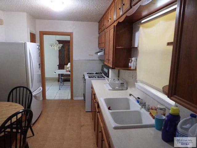 55 Carlton Dr, Brownsville, TX 78521 - kitchen with white appliances, a sink, under cabinet range hood, light countertops, and a textured ceiling