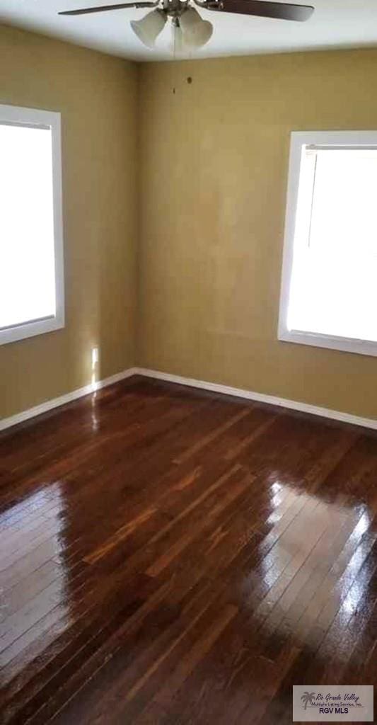 empty room featuring ceiling fan, plenty of natural light, and dark hardwood / wood-style floors