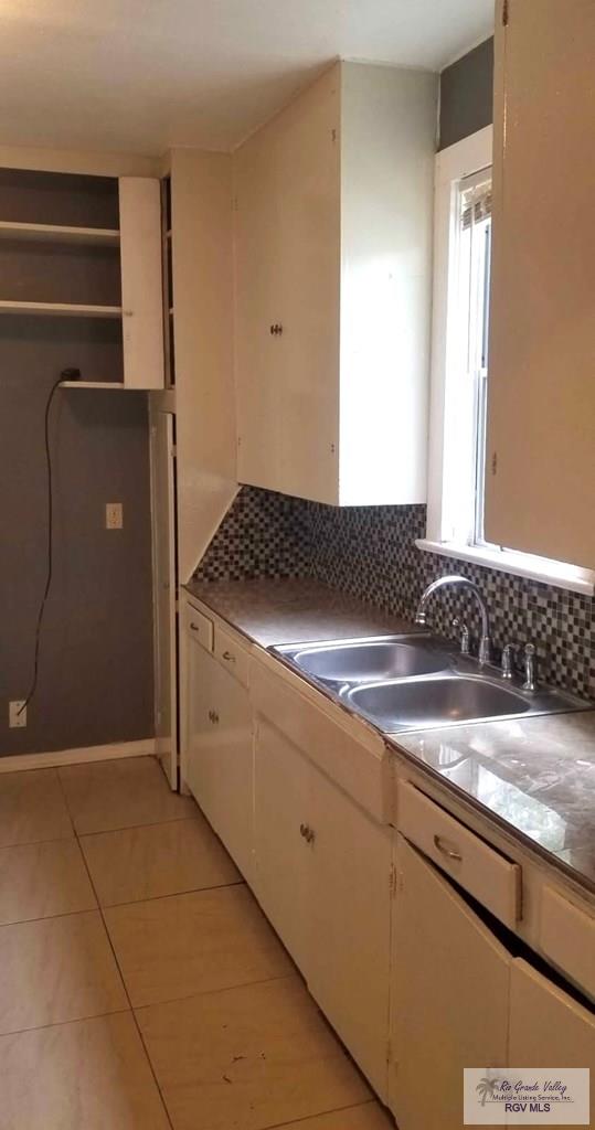 kitchen with white cabinetry, sink, backsplash, and light tile patterned flooring