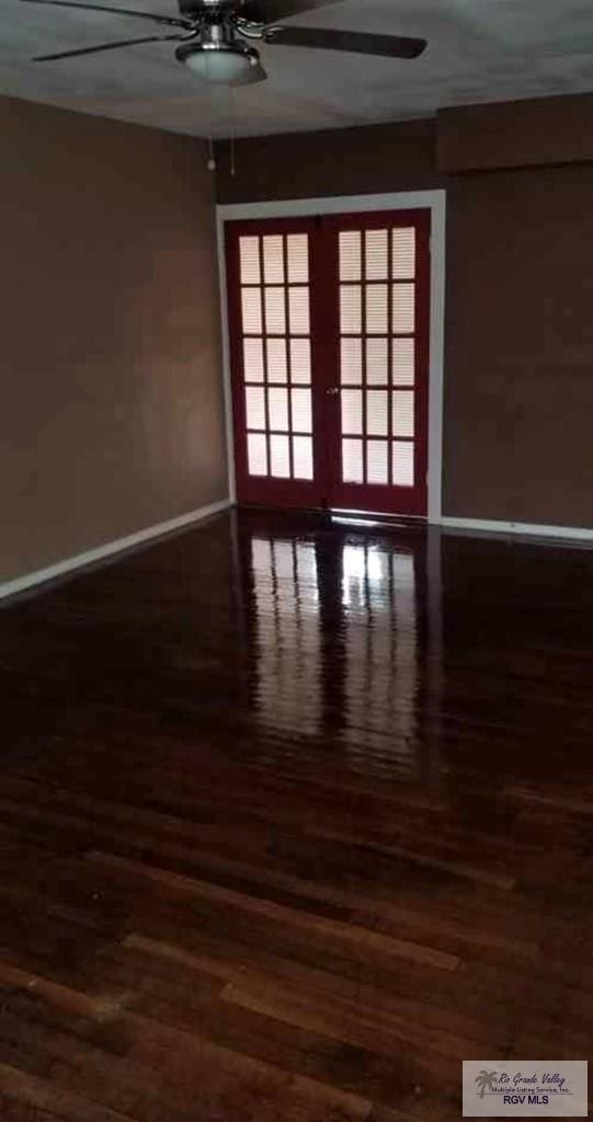 empty room featuring french doors, ceiling fan, and dark hardwood / wood-style floors