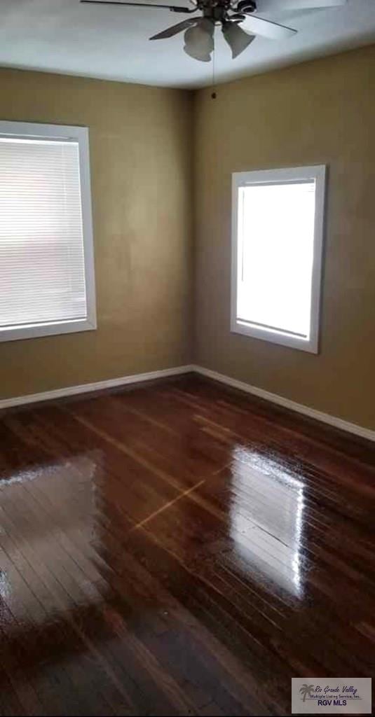 unfurnished room with dark wood-type flooring and ceiling fan