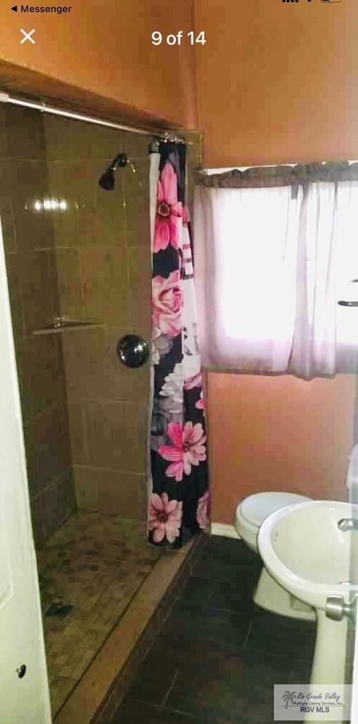 bathroom featuring tile patterned flooring, a wealth of natural light, toilet, and a shower with shower curtain