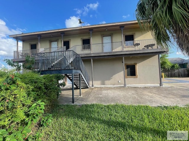 144 N St, Brownsville, TX 78521 - rear view of property with stucco siding, stairway, and a patio
