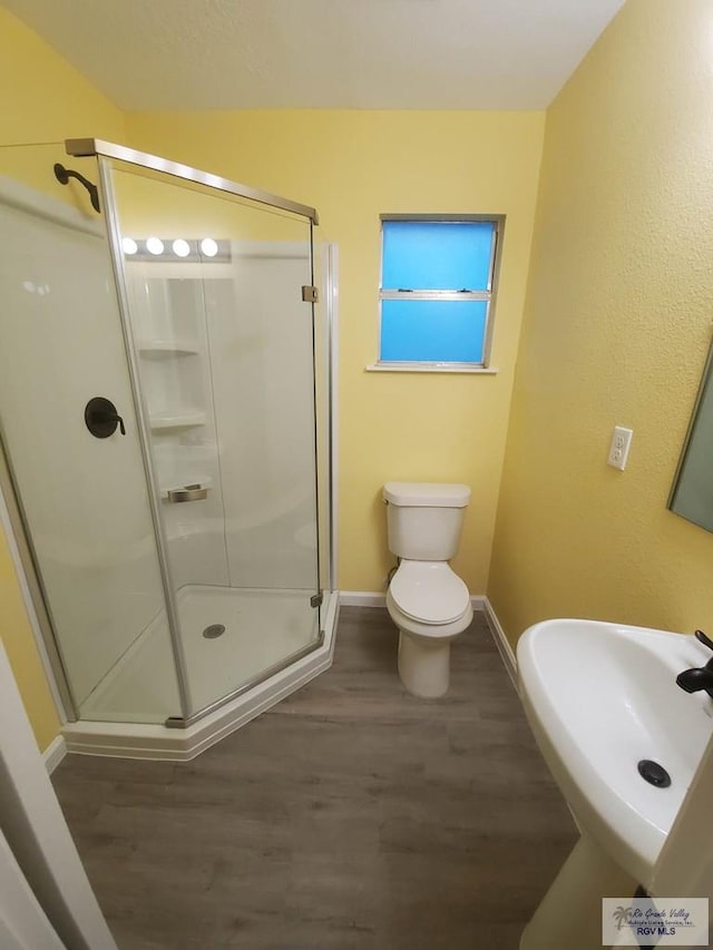 608 W Polk St, Harlingen, TX 78550 - bathroom featuring a shower stall, baseboards, wood finished floors, and a sink