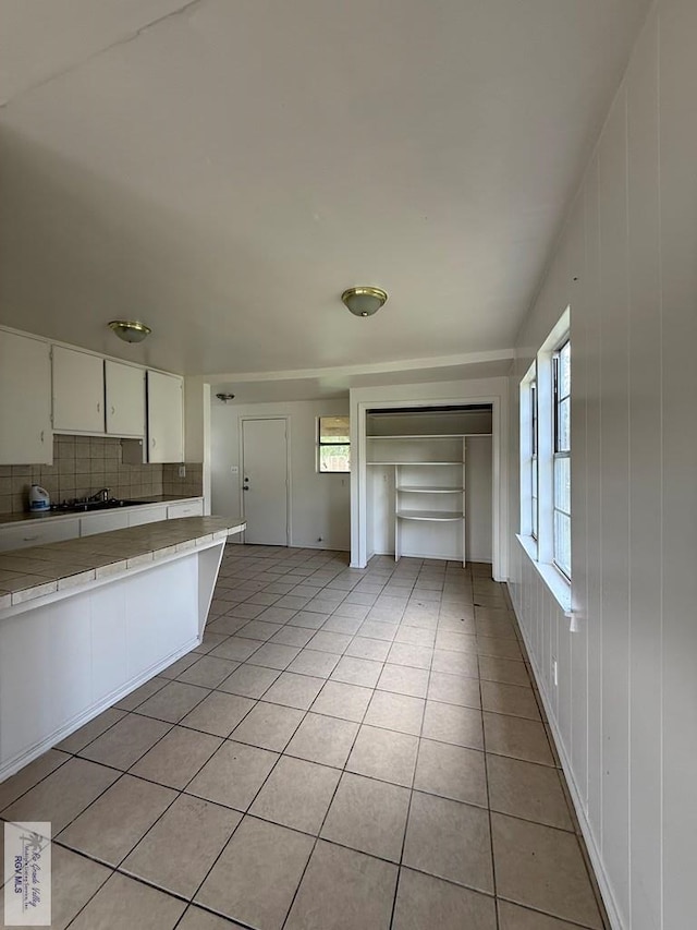 1206 S C St, Harlingen, TX 78550 - kitchen featuring tile counters, light tile patterned floors, decorative backsplash, and white cabinets