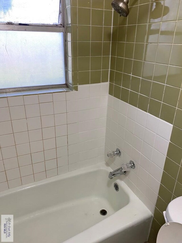 bathroom with tiled shower / bath combo and toilet