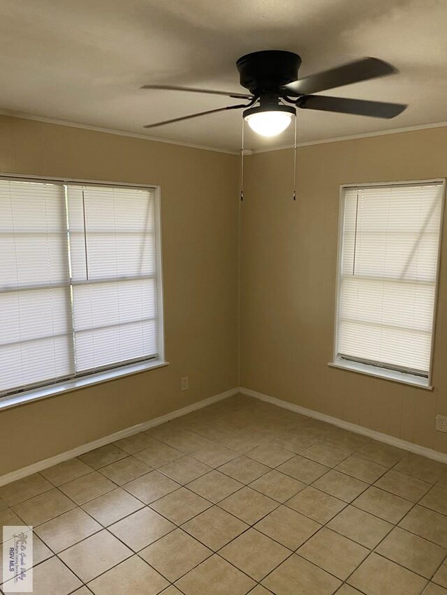 spare room featuring ceiling fan, a healthy amount of sunlight, light tile patterned flooring, and ornamental molding