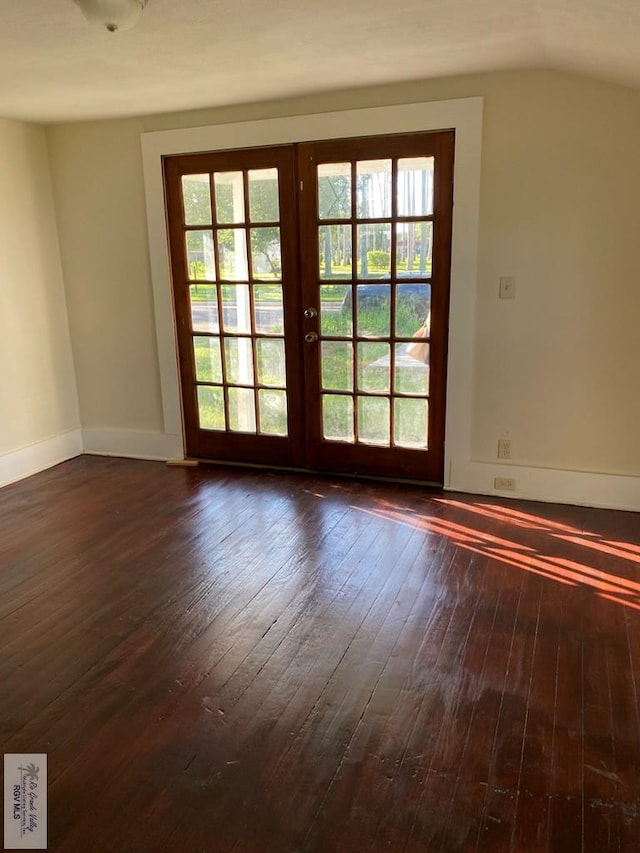 417 SE Verbena Ln Unit 23, La Feria, TX 78559 - spare room featuring french doors, dark wood-style floors, healthy amount of natural light, lofted ceiling, and baseboards