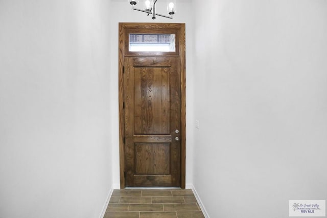 doorway to outside with a notable chandelier and dark wood-type flooring