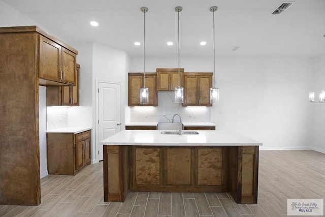 kitchen with light wood-type flooring, tasteful backsplash, hanging light fixtures, and sink