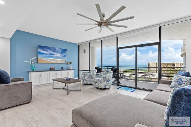 living area featuring floor to ceiling windows, ceiling fan, and a water view