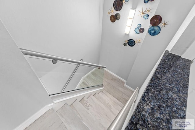 stairway with wood finished floors and baseboards