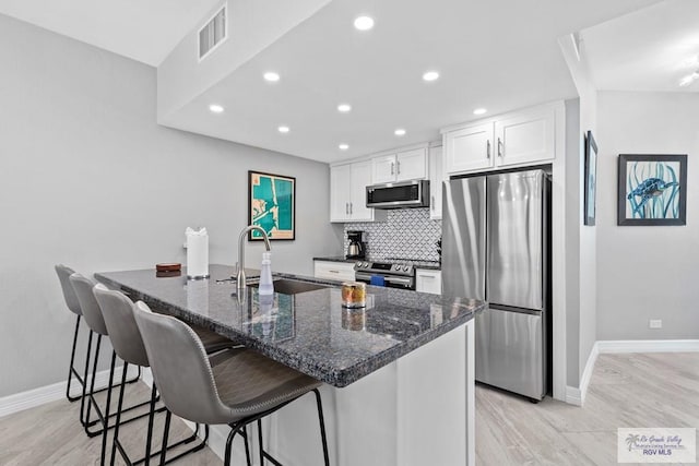 kitchen with visible vents, a sink, tasteful backsplash, white cabinetry, and appliances with stainless steel finishes