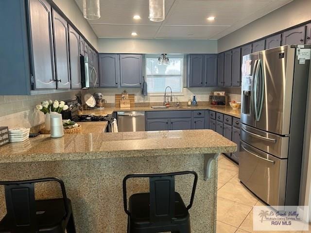 1001 Tesoro Ave, Rancho Viejo, TX 78575 - kitchen featuring appliances with stainless steel finishes, a sink, a peninsula, a kitchen bar, and recessed lighting