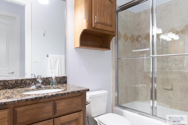 full bathroom with bath / shower combo with glass door, vanity, and toilet