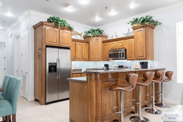 kitchen featuring a breakfast bar area, dark stone countertops, decorative backsplash, stainless steel appliances, and crown molding