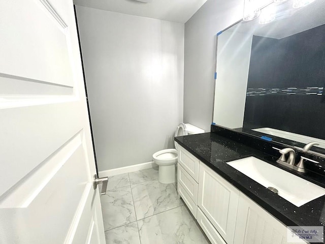 bathroom with marble finish flooring, toilet, vanity, and baseboards