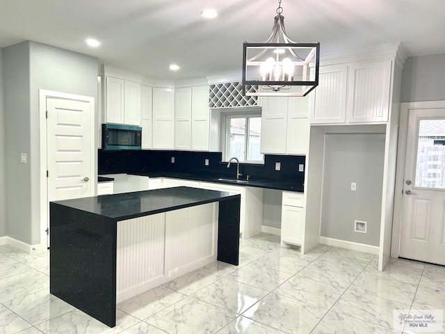 kitchen with light marble finish flooring, white cabinets, a chandelier, a sink, and recessed lighting