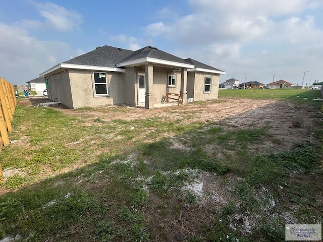 back of property with fence, roof with shingles, and stucco siding