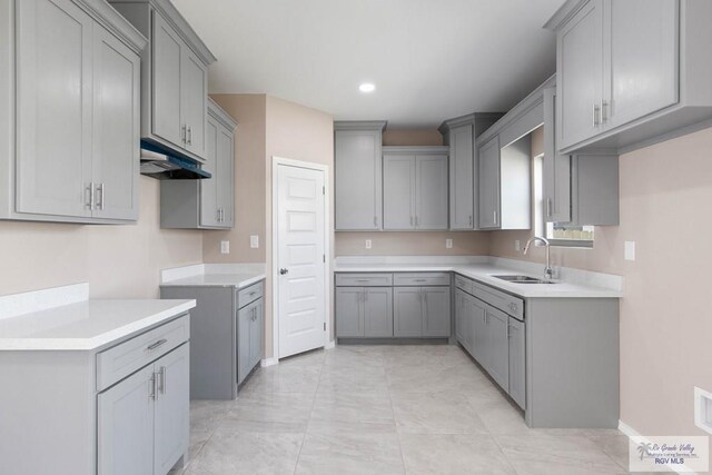 kitchen with gray cabinets, sink, and light tile patterned flooring