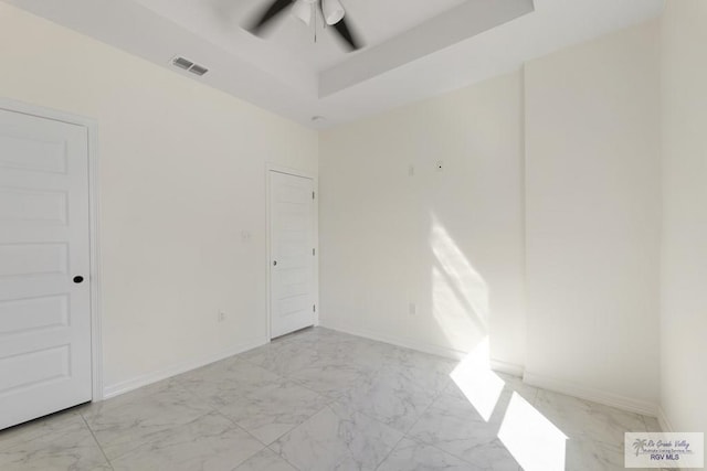 unfurnished room with a ceiling fan, baseboards, visible vents, a raised ceiling, and marble finish floor