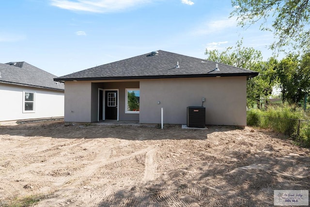 back of property with cooling unit, stucco siding, and a shingled roof