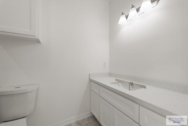 bathroom with baseboards, toilet, marble finish floor, and vanity