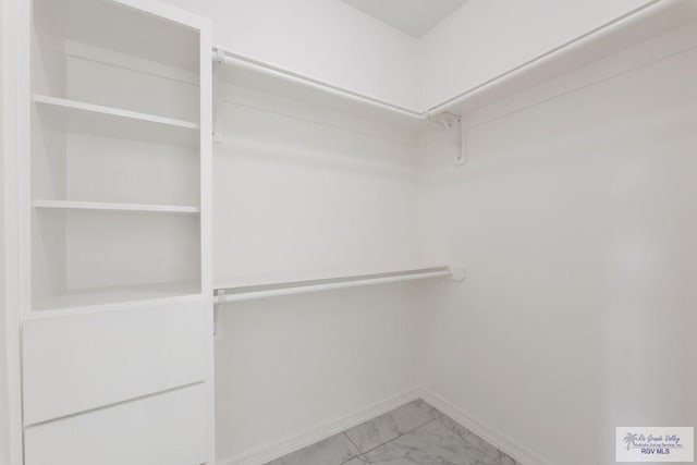 walk in closet featuring marble finish floor