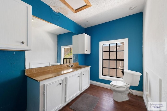 bathroom with hardwood / wood-style floors, vanity, a textured ceiling, and toilet