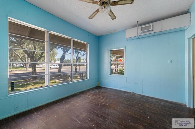 unfurnished room featuring a textured ceiling, a wealth of natural light, ceiling fan, and dark hardwood / wood-style floors